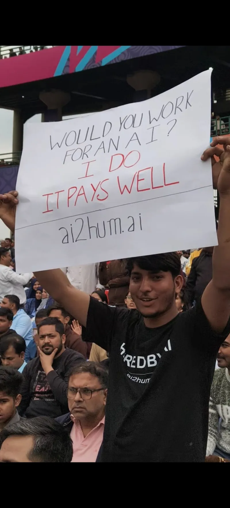 Wear branded t-shirt & hold sign at stadium